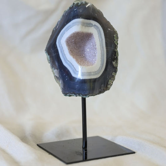 Agaat op een zwarte standaard met een blauwe chalcedoon rand en van binnen kleine Amethist kristallen.