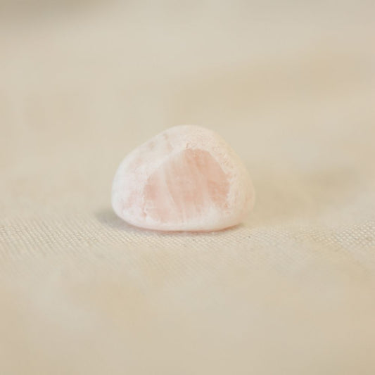 Ema Egg rozenkwarts. Deze edelsteen ziet eruit alsof het in de poedersuiker is gedoopt en aan de andere kant is de steen gepolijst.